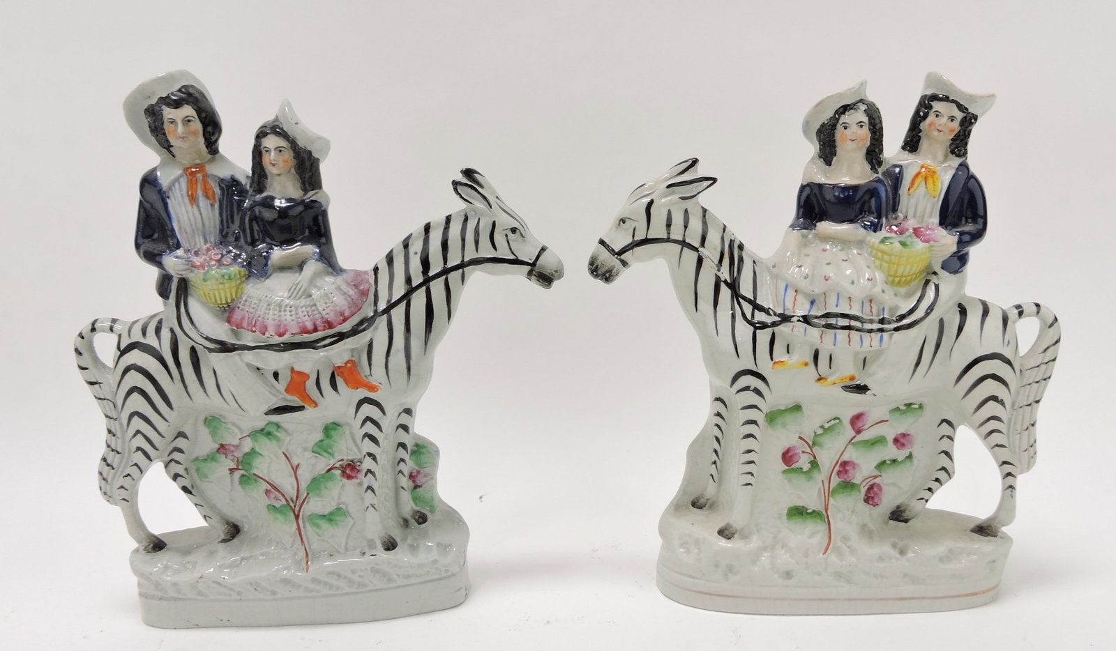 Staffordshire pair of figures of Royal: children riding zebra or striped horse, 9", professional repair to neck of one horse