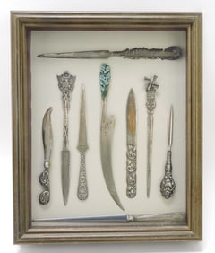 Frame of 9 letter openers, some sterling,
