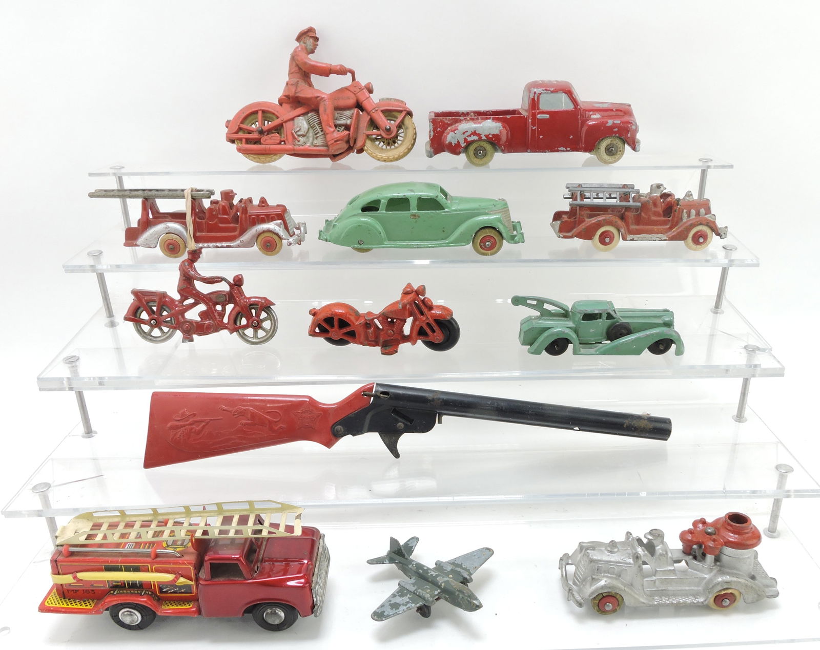 Toy lot of 12 pieces: Auburn Rubber: motorcycle, National Products cast aluminum truck, 3 cast iron Hubley fire trucks, cast iron Hubley car, cast iron motorcycle and rider (missing left arm), cast iron motorcycle, cork gun, tin friction