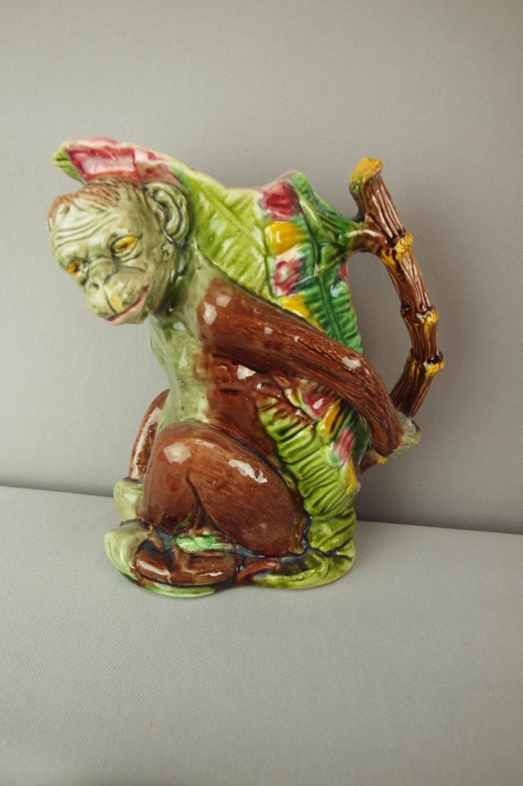 Majolica figural pitcher in the form of a monkey wit: Majolica figural pitcher in the form of a monkey with a bamboo handle, minor surface wear, 8"