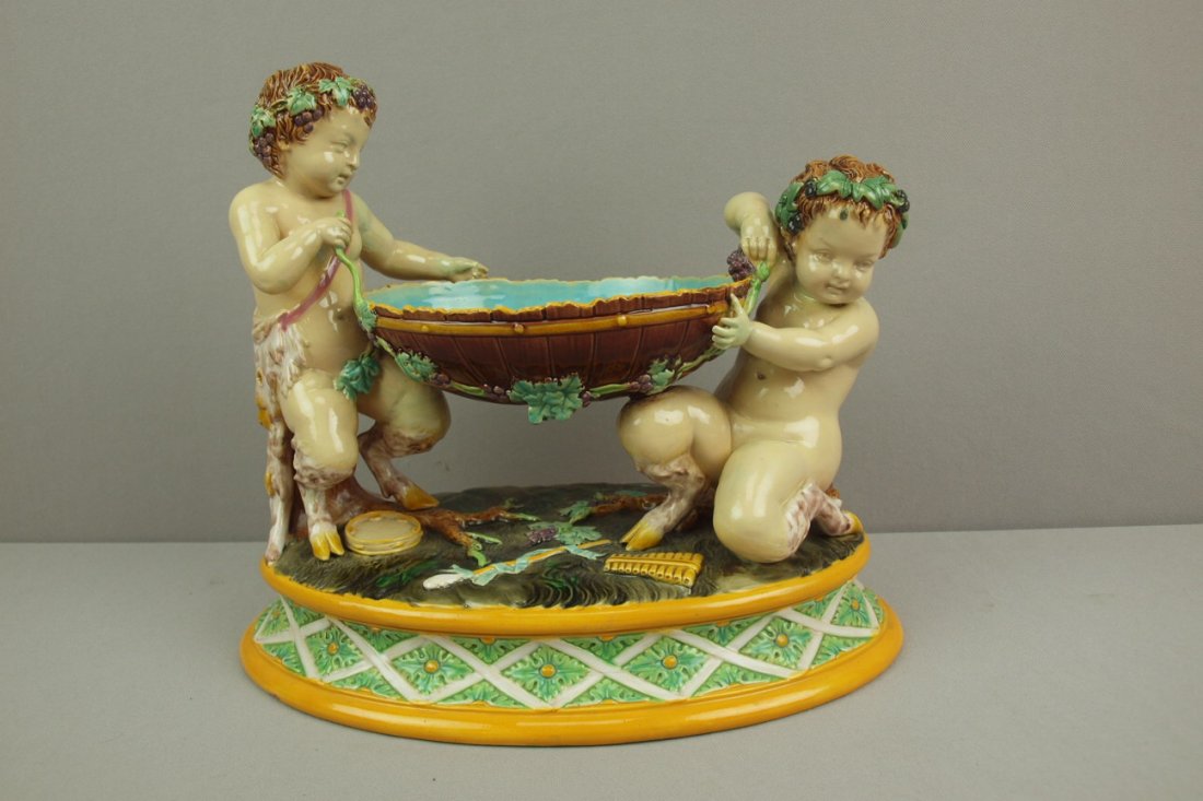 GEORGE JONES majolica table center in the form of tw: GEORGE JONES majolica table center in the form of two putti supporting oval bowl with grapes and vine, 11"h, 12"w, professional repair to legs of one putti
