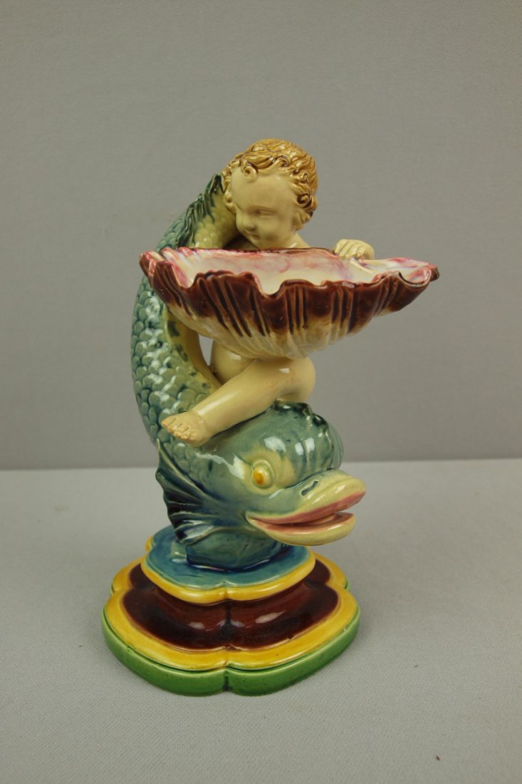 MINTON majolica figural salt in the form of a boy wi: MINTON majolica figural salt in the form of a boy with shell riding dolphin, 7 1/2", professional repair to dolphin's tail