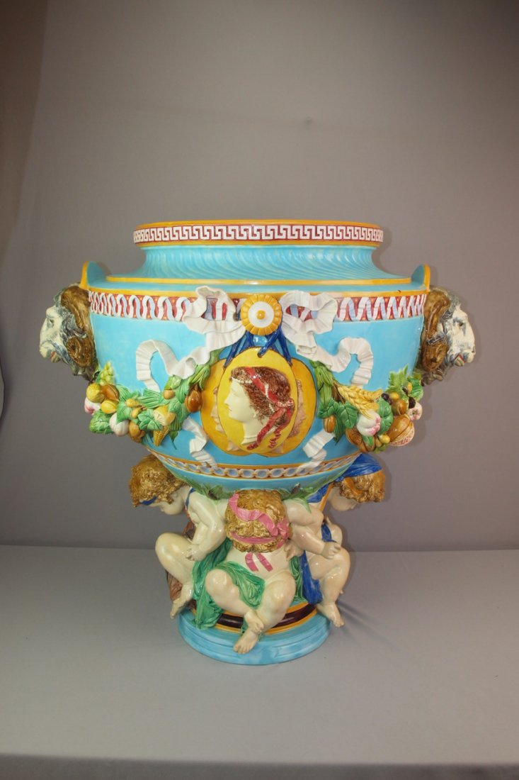 MINTON majolica monumental castle jardiniere with th: MINTON majolica monumental castle jardiniere with three large putti supporting huge jardiniere with garland drapes of fruit supported by large ram heads joined by a medalian on each side, 34"h, 37"w, 