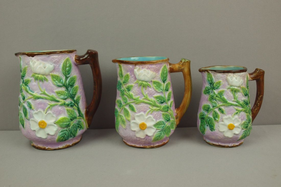 GEORGE JONES majolica set of 3 graduated wild rose p: GEORGE JONES majolica set of 3 graduated wild rose pitchers with pink ground, 7" (professional rim and handle repair), 6 1/2" (rim repair) and 5 1/2" (rim repair)