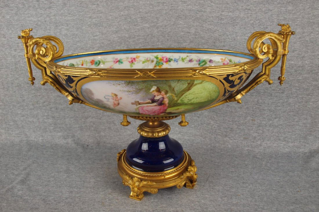 RARE Sevres French porcelain monumental oval table c: RARE Sevres French porcelain monumental oval table center compote decorated with cobalt ground and scene of lady on bench with angels, floral decorated interior, brass mounted base and ormolu rim with