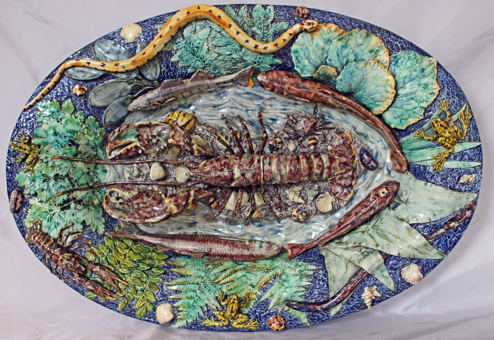 A Monumental Exhibition Quality: Thomas Sergent majolica palissy lobster platter c.1875, the center modelled with a large lobster on a seabed with crab and shellfish detail surrounded by 4 swimming fish, the fern & leaf border with s