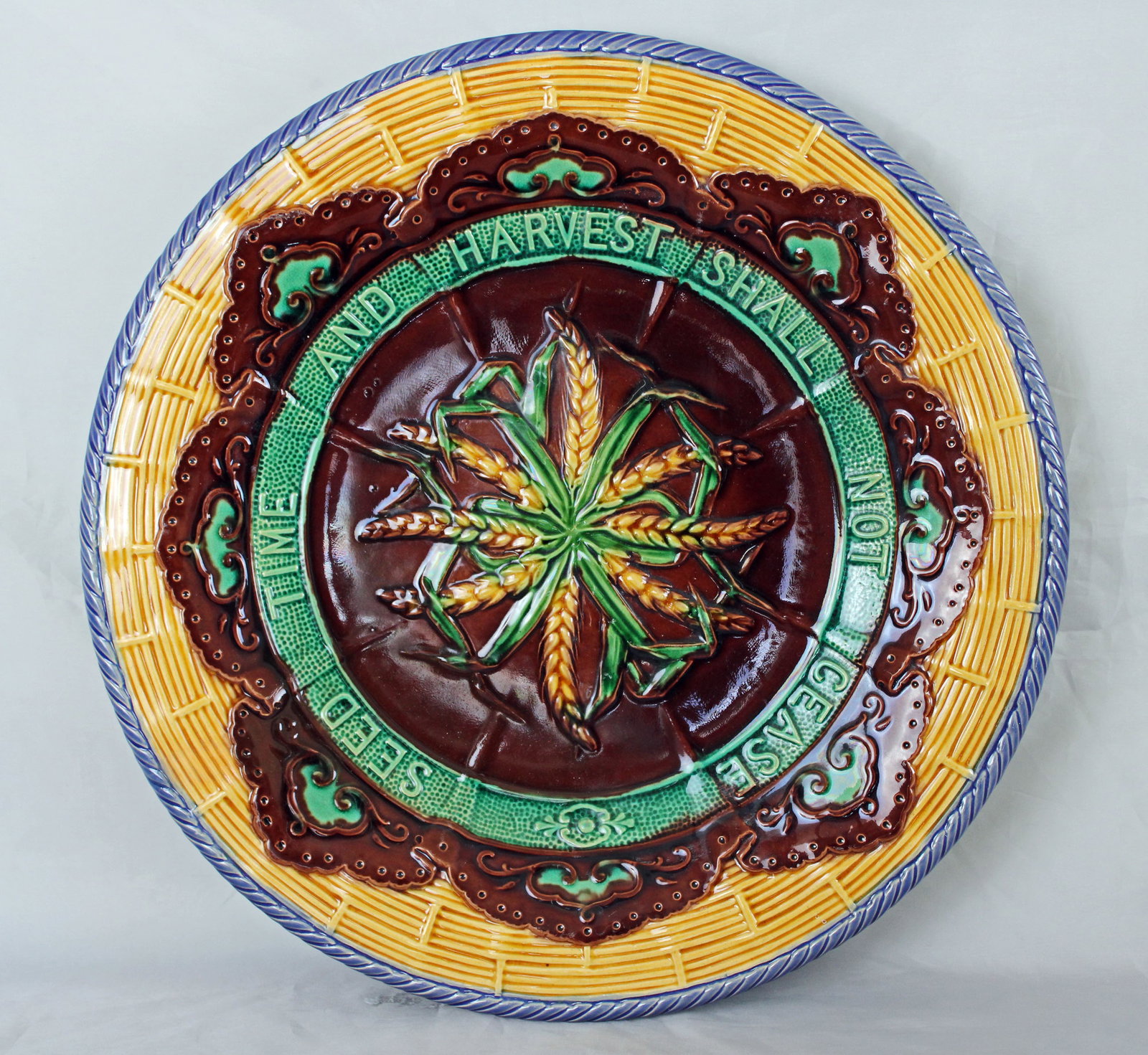 Minton majolica bread tray with wheat sheaves: molded to the center and the motto 'seed time and harvest shall not cease', with a basket ground to the rim, model no. 828 impressed to the underside, 15"w