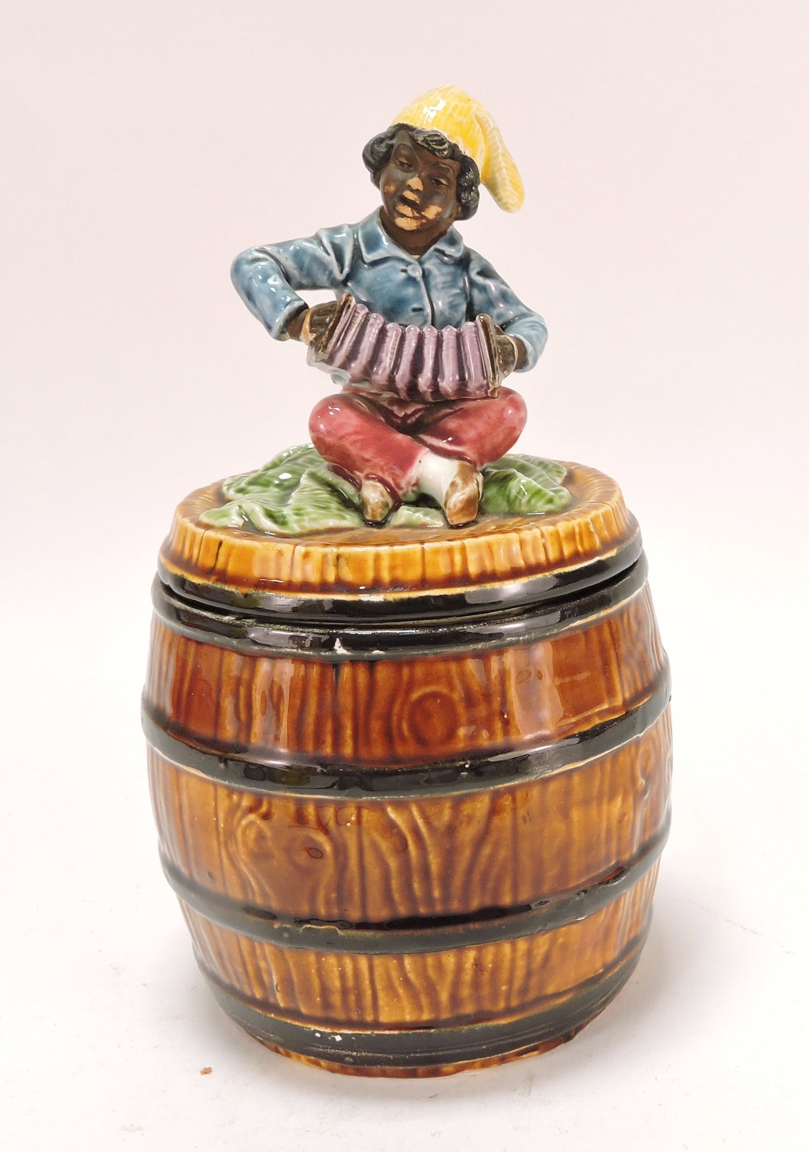 Black Americana majolica humidor: of man with accordion atop a barrel, 9"