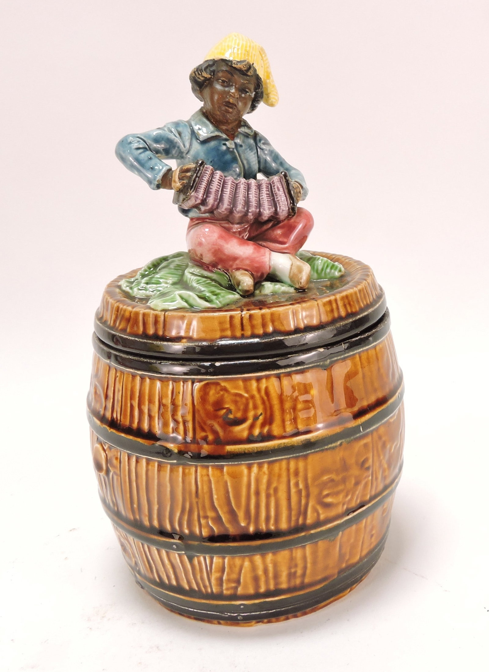 Black Americana majolica humidor: of man with accordion atop a barrel, 9"