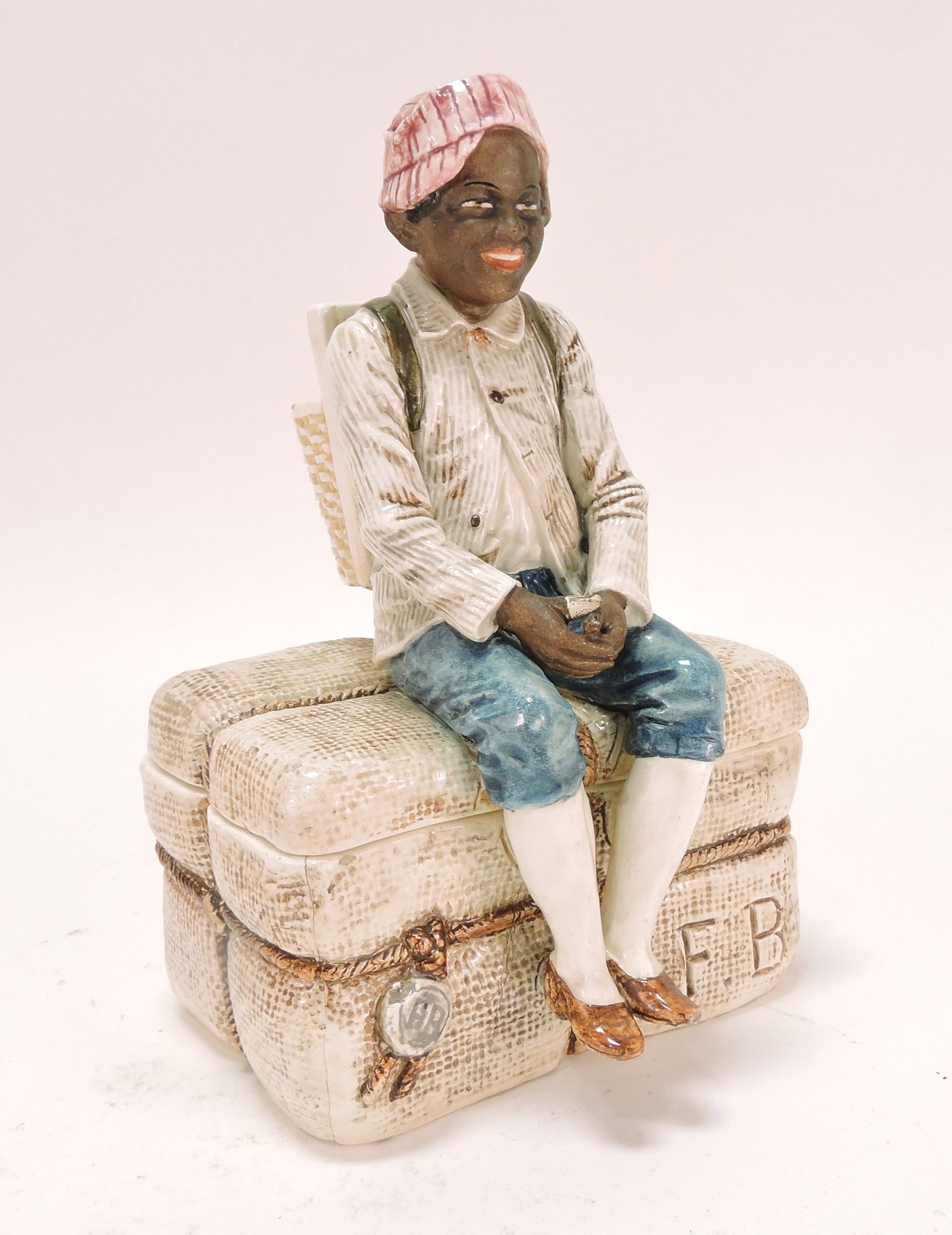 Black Americana majolica humidor: of man with backpack atop a bale of cotton, 7 1/2"
