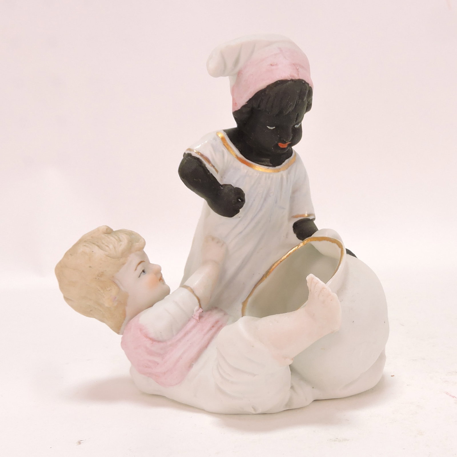 Black Americana bisque figural: of two children frolicking with tea cup, 4 1/4"