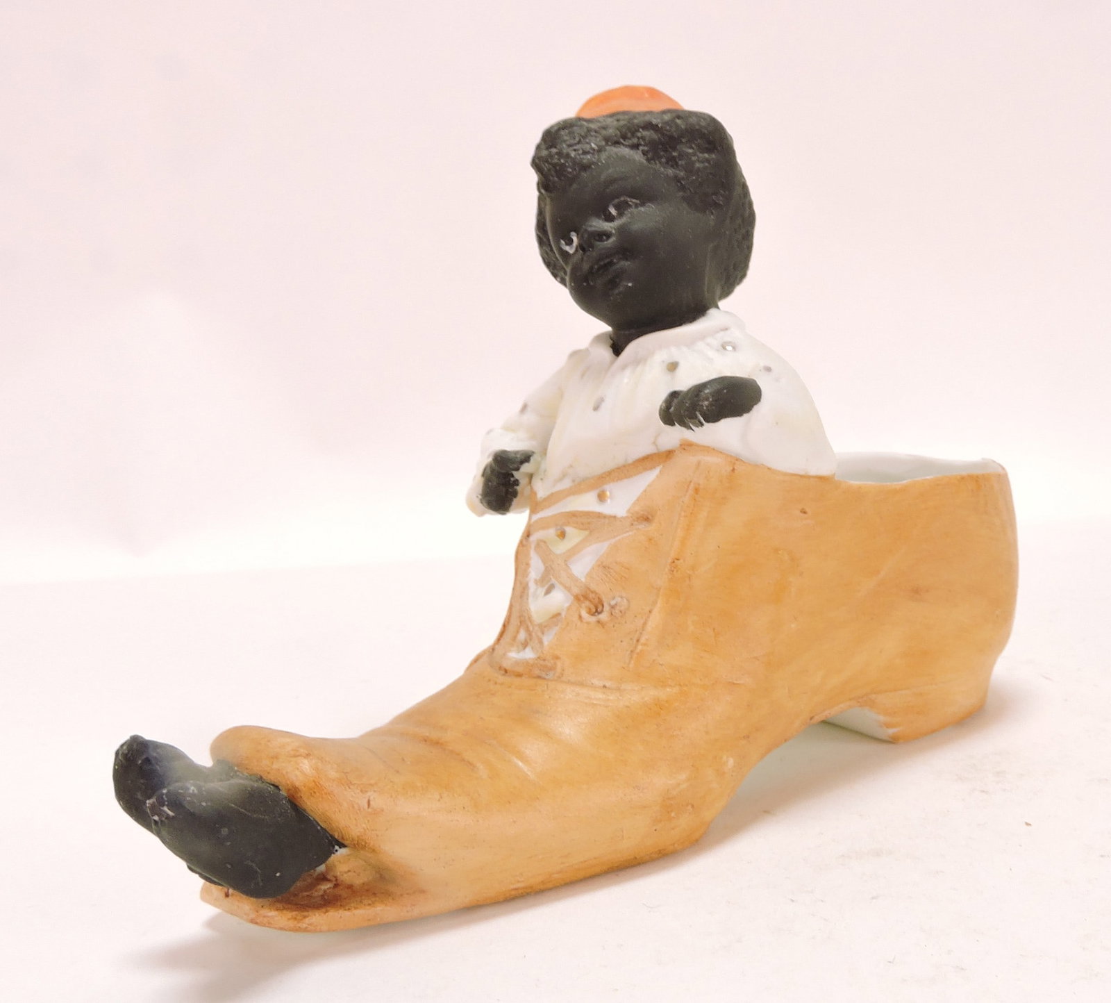 Black Americana bisque figural: match holder of boy in shoe, 4"