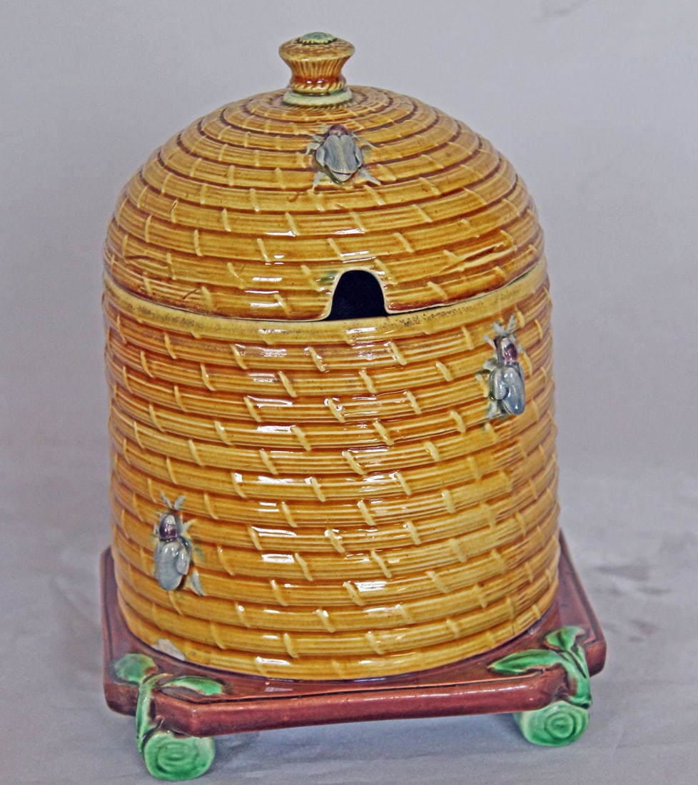 Rare Minton majolica bee honey pot: and cover modelled as a bee skep with bees moulded to the side standing on green log feet, model no 1499, impressed mark to base, date code for 1870