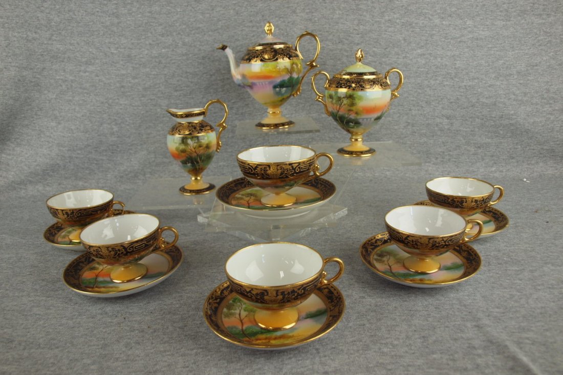 Nippon demitasse teaset with swans on lake, pedestal: Nippon demitasse teaset with swans on lake, pedestal teapot, cream and sugar (minor chip to inside rim under lid of sugar) and 6 cups and saucers, (repair to one), heavy gold accent