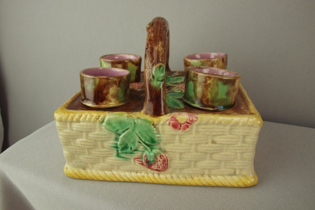 Majolica egg cup holder with strawberries, 4 egg cups,: Majolica egg cup holder with strawberries, 4 egg cups, nicks to base of one egg cup, 6 1/4"l, hairline to holder