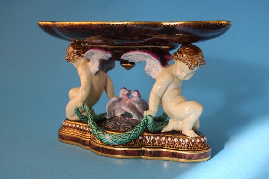 MINTON majolica cherubs and doves center piece on an: MINTON majolica cherubs and doves center piece on an agate ground hgilighted with gilt decoration and enamel beads, circa 1865, 11"l, repair to top tray