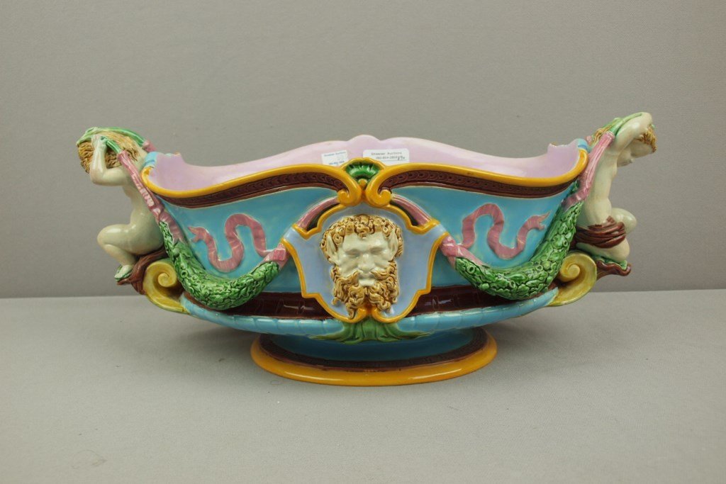 MINTON majolica table center with cherub handles: MINTON majolica table center with cherub handles holding garlands of oak leaves and acorns with mask on each side, 16"l, hairline