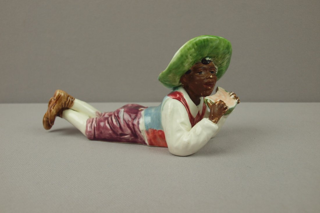 Blackamoor Majolica reclining man eating watermelon, 7": Blackamoor Majolica reclining man eating watermelon, 7" l, professional repair to hat rim