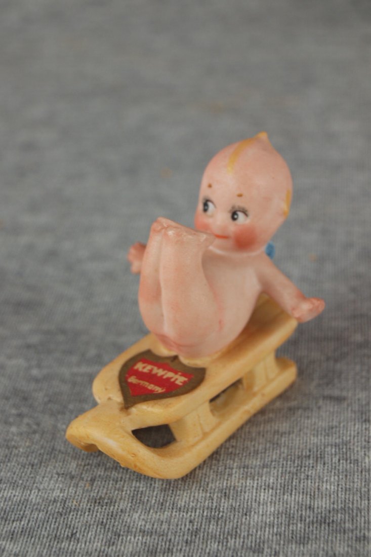 German Rose O'Neil Kewpie bisque figure of Kewpie on: German Rose O'Neil Kewpie bisque figure of Kewpie on sled, with paper label, 2"h, 2 1/2"l
