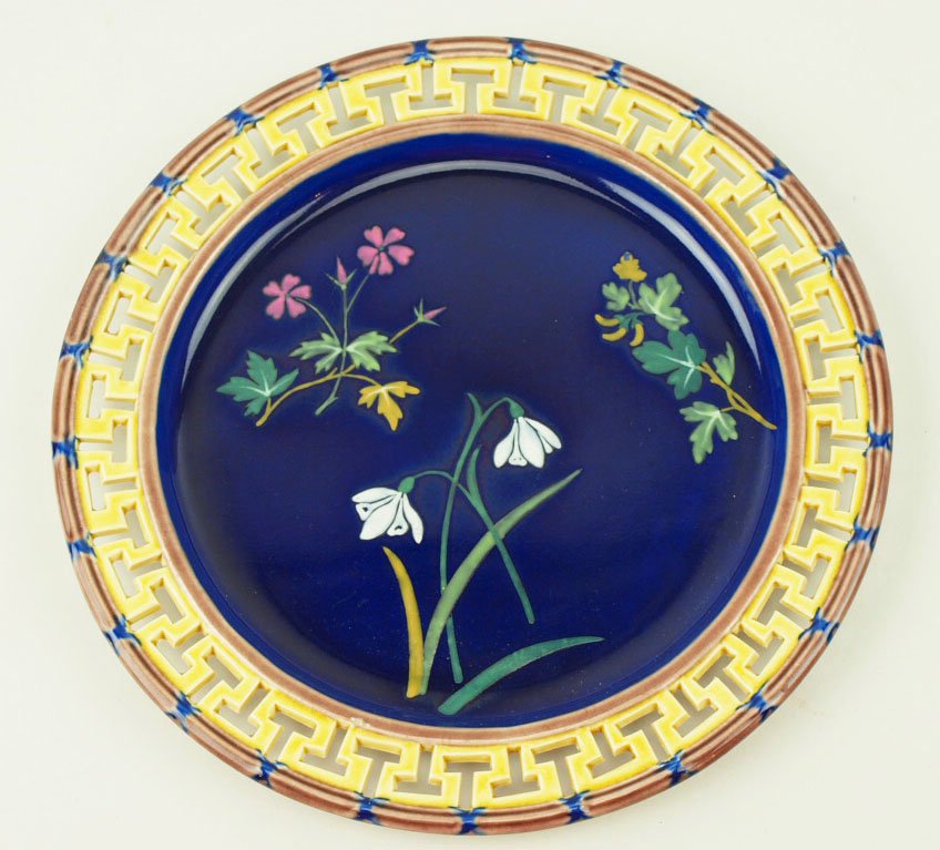 An Excellent Quality Wedgwood Majolica plate, the: An Excellent Quality Wedgwood Majolica plate, the centres with Japanese style floral sprays picked out in bright enamels against a cobalt ground and yellow border with a carved greek key pattern with