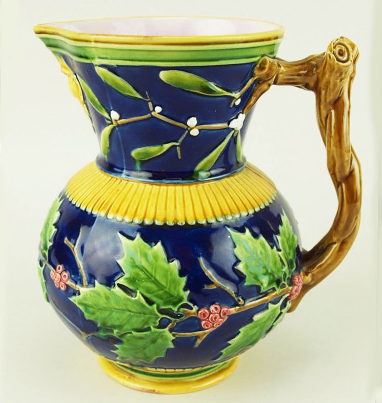 An excellent quality Minton Majolica ‘Christmas’: An excellent quality Minton Majolica ‘Christmas’ pitcher c.1875 with a round body decorated with holly, the neck with mistletoe, and a mask handle under the spout, all on a cobalt ground with an e