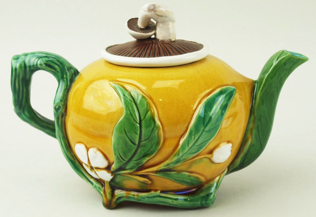 A Minton Majolica mushroom teapot c.1875, the yellow: A Minton Majolica mushroom teapot c.1875, the yellow body supported on twig feet, decorated with large green leaves and blossoms, with a green twig handle and a mushroom to form the lid, date code 186