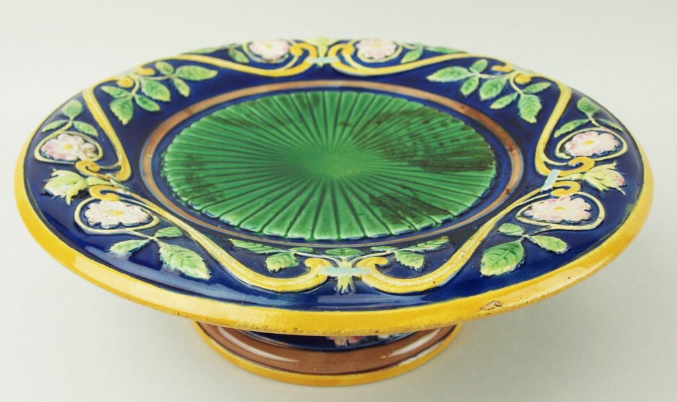 A George Jones low dessert compote decorated with: A George Jones low dessert compote decorated with radiating emerald green centres, a deep cobalt blue border and stylized scrolling, leaves, and blossoms with an orange border, 9” 'CURATED & CATALOG