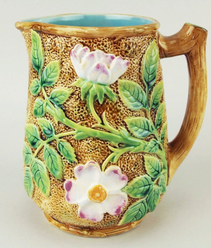 A George Jones ‘wild rose’ pitcher. c.1875, the pitted: A George Jones ‘wild rose’ pitcher. c.1875, the pitted light brown body decorated with large wild roses and leaves with a branch handle and turquoise interior, 6 ¾” 'CURATED & CATALOGUED BY NIC