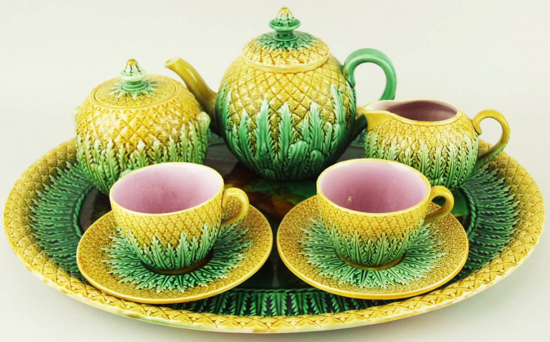 A rare Adams and Bromley Majolica pineapple cabaret: A rare Adams and Bromley Majolica pineapple cabaret set c1875, 16”l, each piece with pineapple and leaf decoration, the serving pieces all with pink interior, the tray with a mottled green and brown