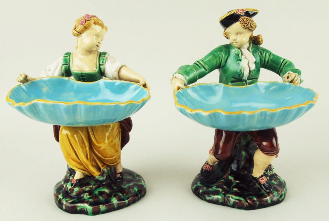 A fine pair of Minton Majolica ‘Hogarth Match boy’ and: A fine pair of Minton Majolica ‘Hogarth Match boy’ and Hogarth Match Girl’ c.1870, designed by Albert Carrier Bellouse, modeled as a boy and girl in 18th century costume, each carrying a turquoi
