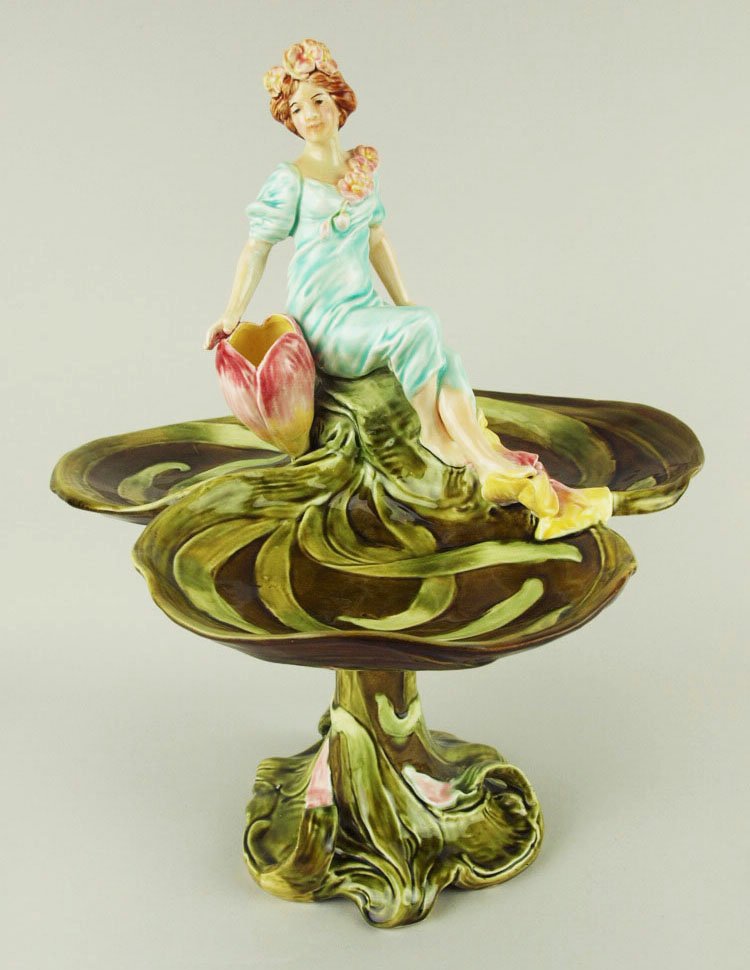 A rare Royal Dux style Majolica centrepiece in the Art: A rare Royal Dux style Majolica centrepiece in the Art Nouveau style c.1890. Modeled as a maiden in turquoise gown sat on a green leafy pedestal with an open flower posy holder and three bowls beneath