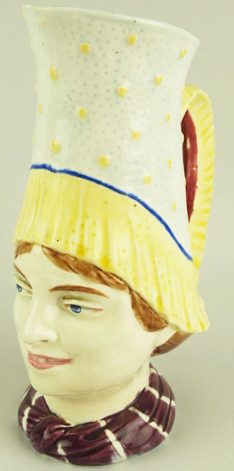 A Rare Sarreguemines Majolica water pitcher “Normandy”: A Rare Sarreguemines Majolica water pitcher “Normandy” c.1880 shape # 1752. Modeled as a woman wearing a high traditional Normandy hat and a burgundy and white neck scarf. Provenance: Helen Cunnin