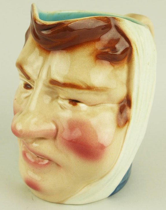 A Sarreguemines Majolica pitcher “The Headband”: A Sarreguemines Majolica pitcher “The Headband” c.1880, shape 2221. Provenance: Helen Cunningham.Modeled as a man with a toothache with a bandage around his head.This design is often referred to a
