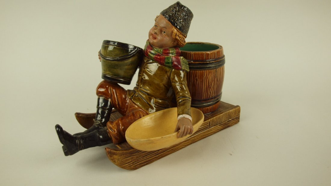 Majolica figural match striker smoking set in the form: Majolica figural match striker smoking set in the form of a boy on sled, signed BB, repair to back corner of sled, 9"l