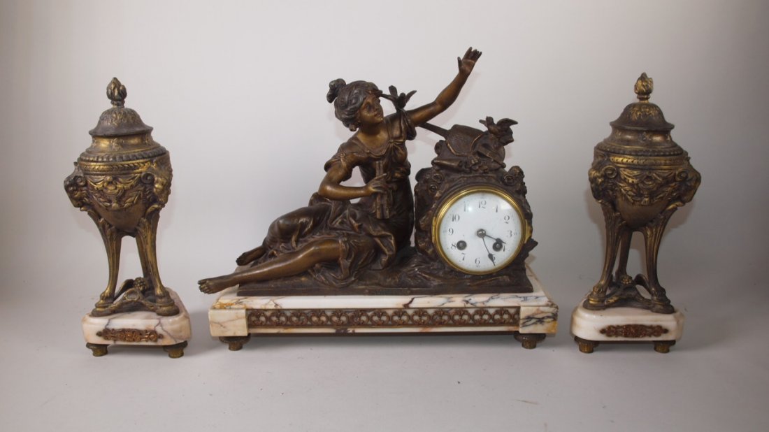 French pink marble figural clock with 2 spelter: French pink marble figural clock with 2 spelter garnitures with pink mobile bases, clock 14"w x 12 1/2", garnitures 11 1/2", repair to finial of one garniture, "Chermeuse" by Moreau