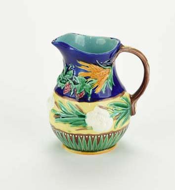A Wedgwood Majolica ‘Burton’ Pitcher c.1875 The: A Wedgwood Majolica ‘Burton’ Pitcher c.1875 The baluster shaped body with a lower panel of upright acanthus and a yellow ground belly decorated with bulrushes and white blossoms, the cobalt blue u