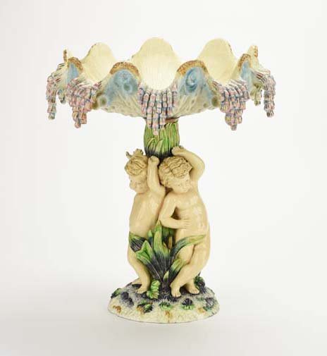 A Rare Hugo Lonitz Centerpiece Bowl, c. 1880: A Hugo Lonitz Majolica Centerpiece Bowl, c. 1880. Modeled as three putto around a green leaf pedestal supporting a conch shell shaped circular bowl above, all on a circular earthy ground, 16 1/2"h, 15