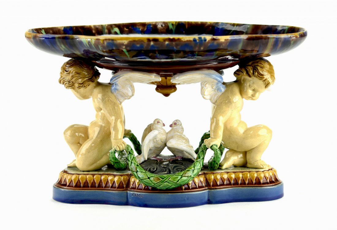 A Minton Majolica Oval Mantle Bowl. c.1860 Modeled two: A Minton Majolica Oval Mantle Bowl. c.1860 Modeled two back to back winged putti, holding laurel swags and supporting a shaped oval cobalt blue dish with turquoise interior, beneath, two white tur
