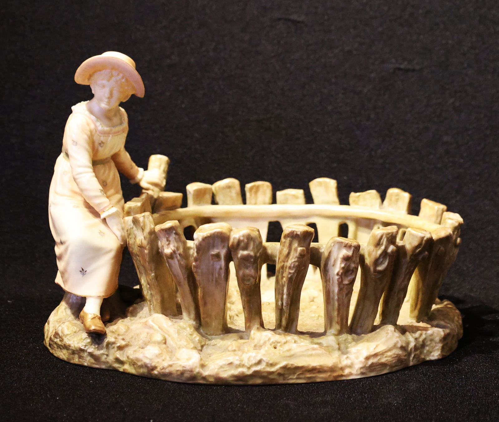 Antique Royal Worcester Figural Basket Modeled By James Hadley Around The 1880s.: antique Royal Worcester figural basket or spill holder, modeled by James Hadley around the 1880s. The piece features a woman in period clothing standing beside a rustic, fence-like basket. ; Size: 8 i