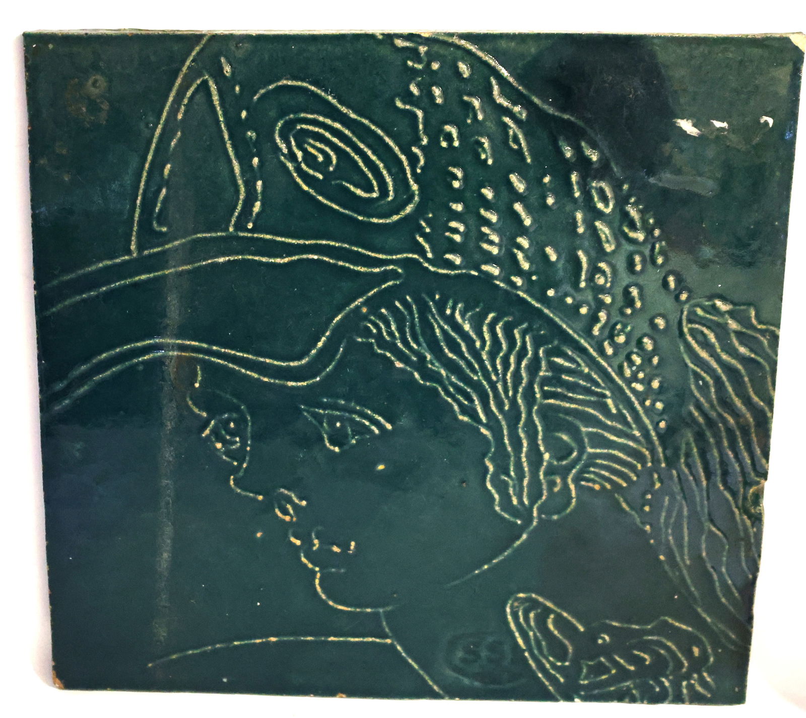 Vintage Art Pottery Portrait Tile From the SSK Studio, Created by artists Susan & Steven Kemenyffy: vintage art pottery tile from the SSK Studio, created by artists Susan & Steven Kemenyffy. It features a dark green glaze with a raised, detailed line design. The subject matter often depicts whimsica