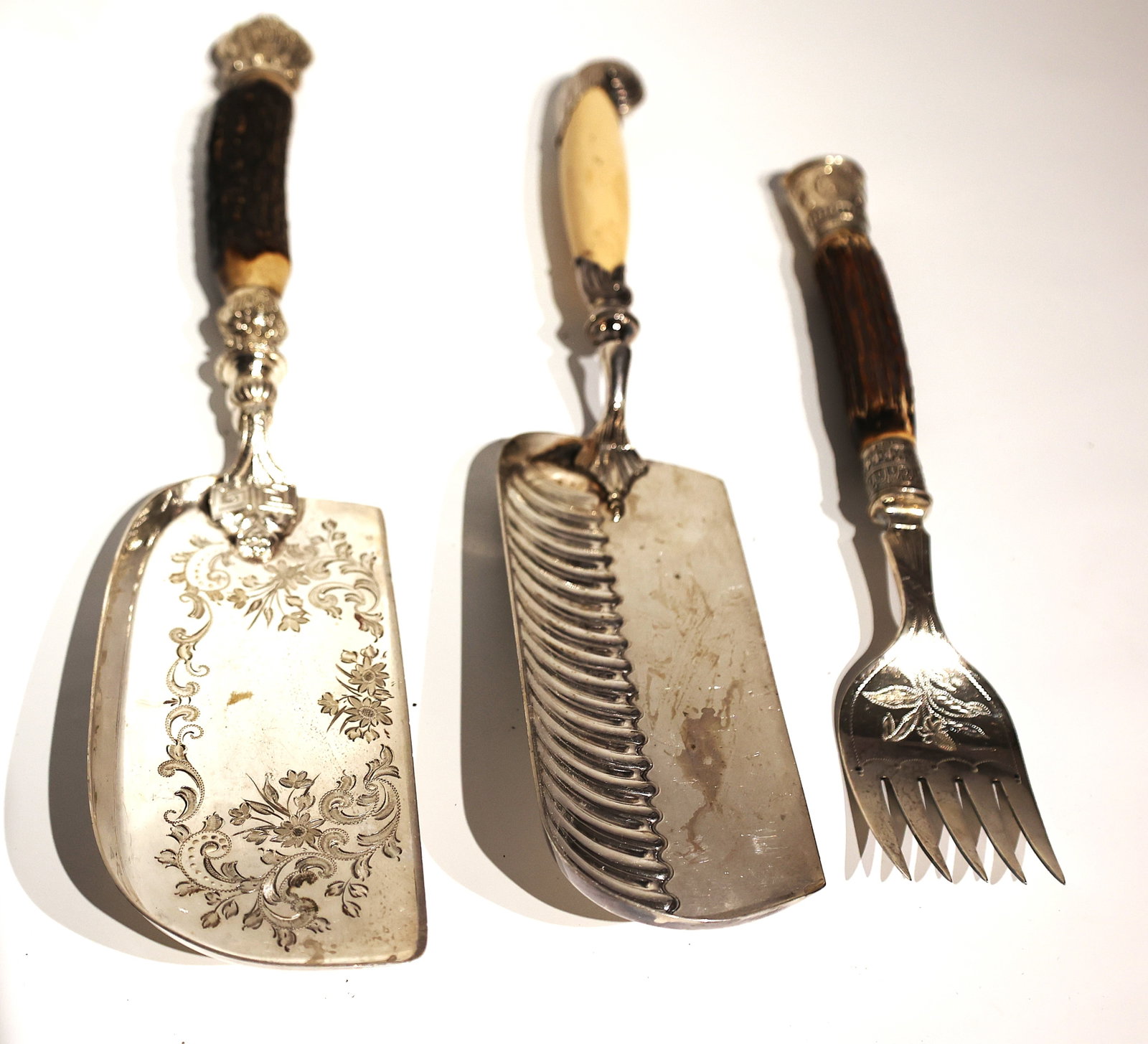 2 Antique Victorian-era Silver-plated Crumb Scoops Engraved Design and Stag Horn Antler Handles: 2 antique Victorian-era silver-plated crumb scoops set featuring engraved floral patterns and natural stag antler handlesm and horn handled fork. Size: 14.5 inches x 3 inches; 13.5 inches x 2 3/4 inch