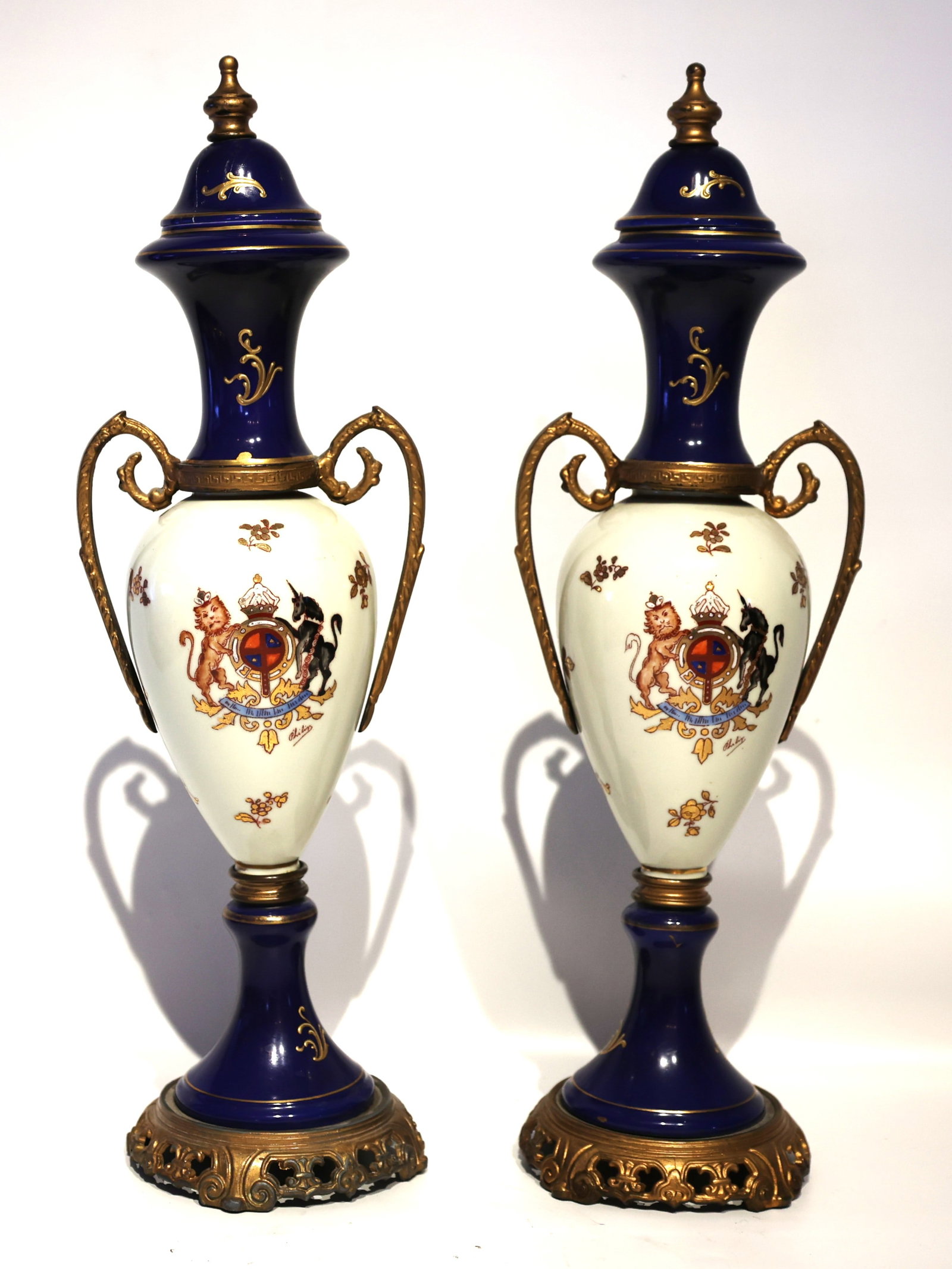 Pair of Early 20th-Century French Sèvres-style Porcelain Garnitures, Crest with a Lion and Unicorn.: pair of early 20th-century French Sèvres-style porcelain Garnitures, featuring ornate gilt-bronze mounts and handles. Material: Cobalt blue and white porcelain with gilded bronze elements. Design: Ne