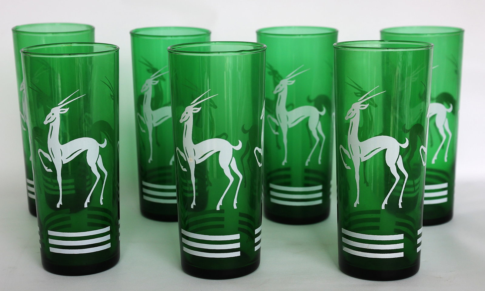 7 vintage green glass Collins tumblers, often attributed to Hazel Atlas or Anchor Hocking, Gazelle: Size: 6 1/2 in. height x 2 3/4 in. wide ; 7 These are vintage green glass Collins tumblers, often attributed to Hazel Atlas or Anchor Hocking, featuring a distinctive white gazelle motif