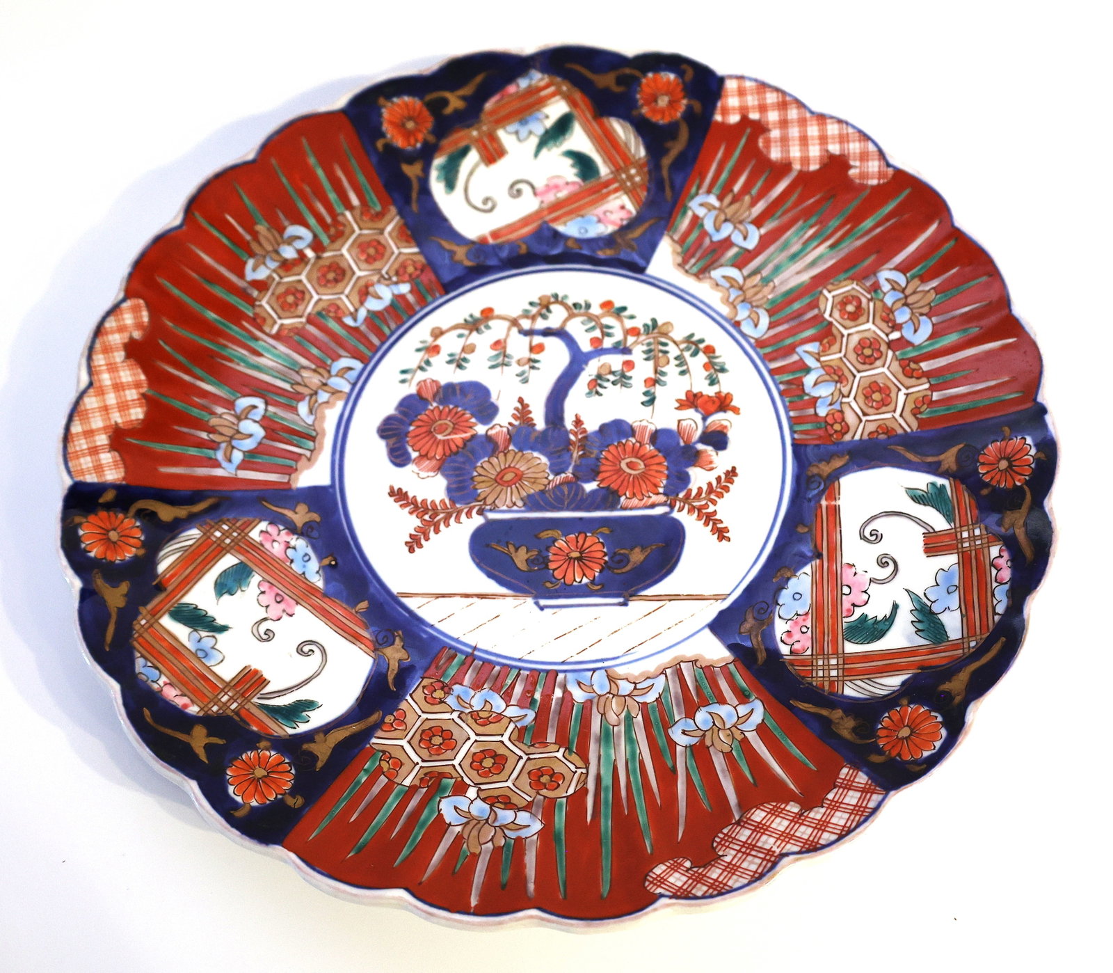 antique Japanese Arita Imari plate from the Edo or Meiji period, featuring a distinct scalloped edg: Size: 12 in. diameter; antique Japanese Arita Imari plate from the Edo or Meiji period, featuring a distinct scalloped edge.It is hand-painted with traditional red, blue, and white porcelain floral de