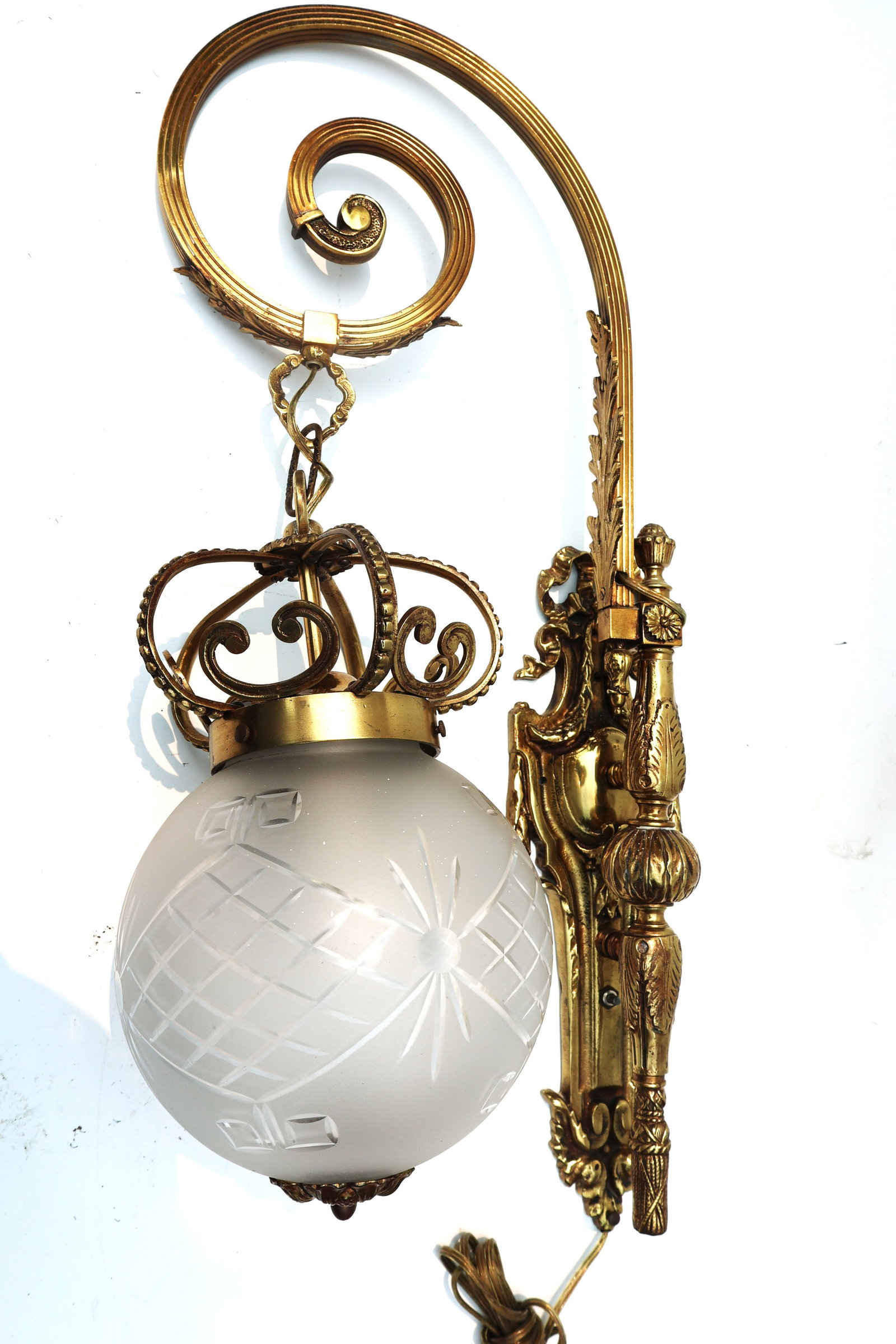 vintage wall sconce featuring an ornate brass arm and a frosted glass globe shade (1 of 5)