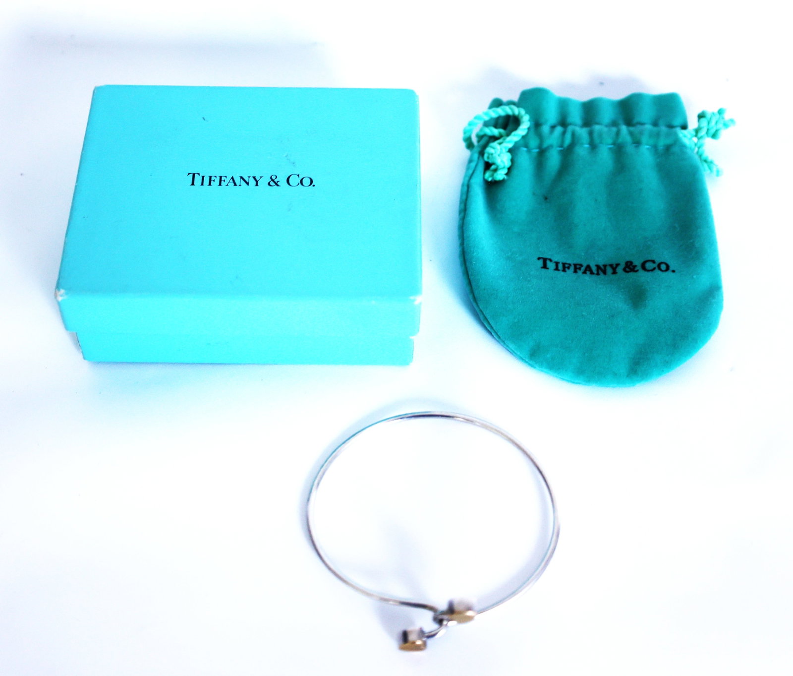 Tiffany & Co .925 Sterling Silver and 750 [18K Gold] 9 Grams Interlocking Double Heart Hook Bangle: Tiffany & Co .925 Sterling Silver and 750 [18K Gold] 9 Grams Interlocking Double Heart Hook Bangle Bracelet. Size: 2 1/2 in. x 1/2 in. ; with original Pouch and Box