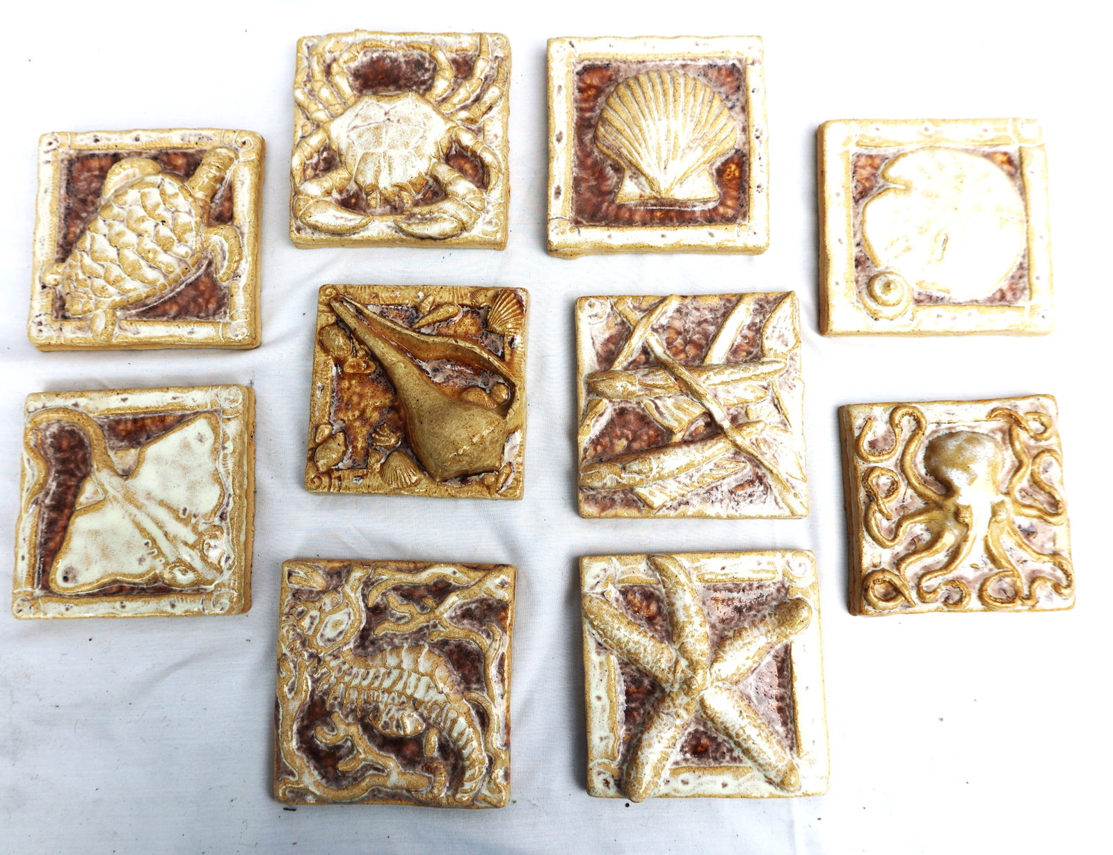 10 handmade ceramic or stoneware craft tiles with a nautical or marine life theme.They feature raise: Size: 4 in. x 4 in. ; 10 handmade ceramic or stoneware craft tiles with a nautical or marine life theme.They feature raised relief designs of various sea creatures, including a crab, octopus, sea turt