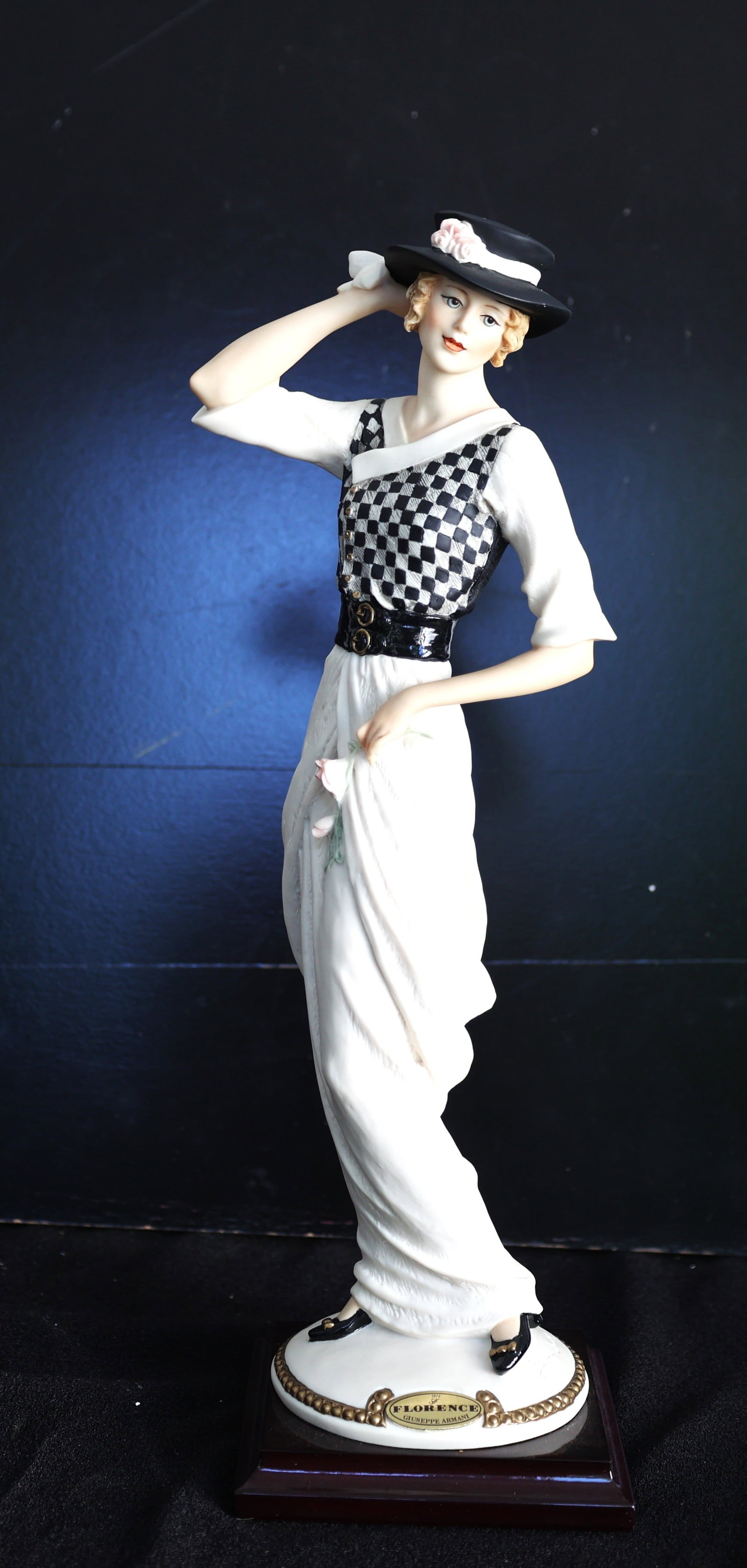 Giuseppe Armani Florence figurine is titled "Kathy-Novecento" and features a woman in a black and wh: Size: 13 1/4 in. height, 4 1/2 in. wide, 4 in. x 4 in. base; Giuseppe Armani Florence figurine is titled "Kathy-Novecento" and features a woman in a black and white checkered top and a black hat, with