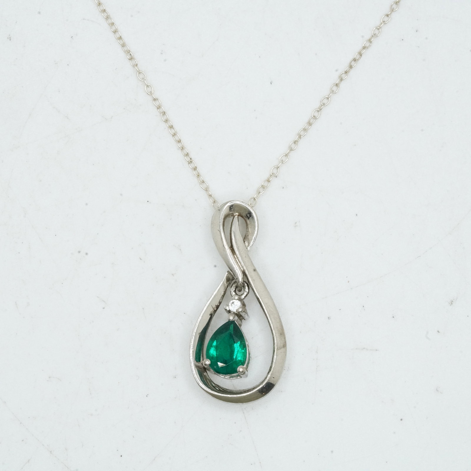 .925 Sterling Silver 3.13 Grams, Emerald and Small Diamond Pendant Infinity Swoop Necklace: .925 Sterling Silver 3.13 Grams, Emerald and Small Diamond Pendant Infinity Swoop 1/2 in. x 1 in. Necklace on .925 Sterling Siver Italy 17 in. Chain.