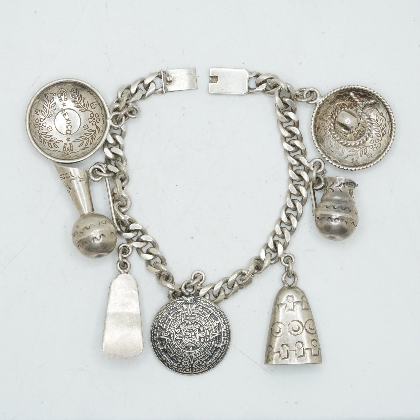 38.38 Grams .925 Sterling Silver Temchaica Mexico Cuban Link Bracelet with 7 Sterling Charms: 38.38 Grams .925 Sterling Silver Temchaica Mexico Cuban Link Bracelet with 7 Sterling Charms; Size chain 7 in. x 1/4 in; Charms average 1 in.